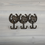Three bronze cast iron horse head hooks with scrolled brackets, rustic wall rack