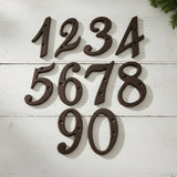 Rustic cast iron house numbers 1234-5678-90, antique dark brown metal address set on white wood wall