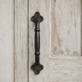 Black cast iron barn door pull handle mounted on distressed white wood door