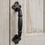 Close-up of black cast iron door pull handle with clover mounting plates and screws