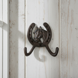 Cast iron horseshoe with detailed horse head design and double curved coat hooks