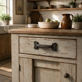 Cast iron drawer pull installed on a rustic kitchen cabinet drawer