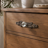 Antique brown cast iron scroll backplate with clear glass drawer knob on wood drawer
