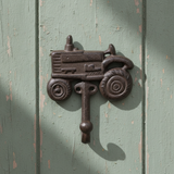 Cast iron tractor hook with detailed wheels and seat, antique brown finish mounted on wall