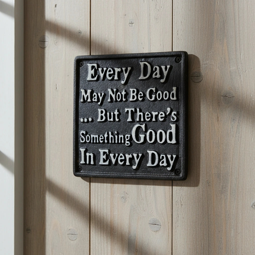 Black cast iron inspirational plaque with white text on rustic wood wall