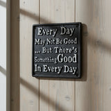 Black cast iron inspirational plaque with white text on rustic wood wall