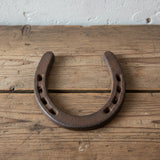 Antique cast iron horseshoe with nail holes mounted on wooden wall, rustic good luck decor