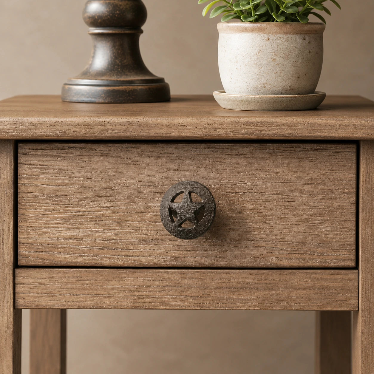 Straight-on view of black cast iron star wheel drawer knob on a wooden cabinet