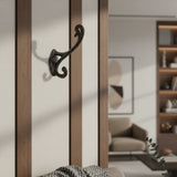 Decorative black wall hook on a wooden wall with a blurred living room background