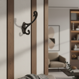 Decorative black wall hook on a wooden wall with a blurred living room background