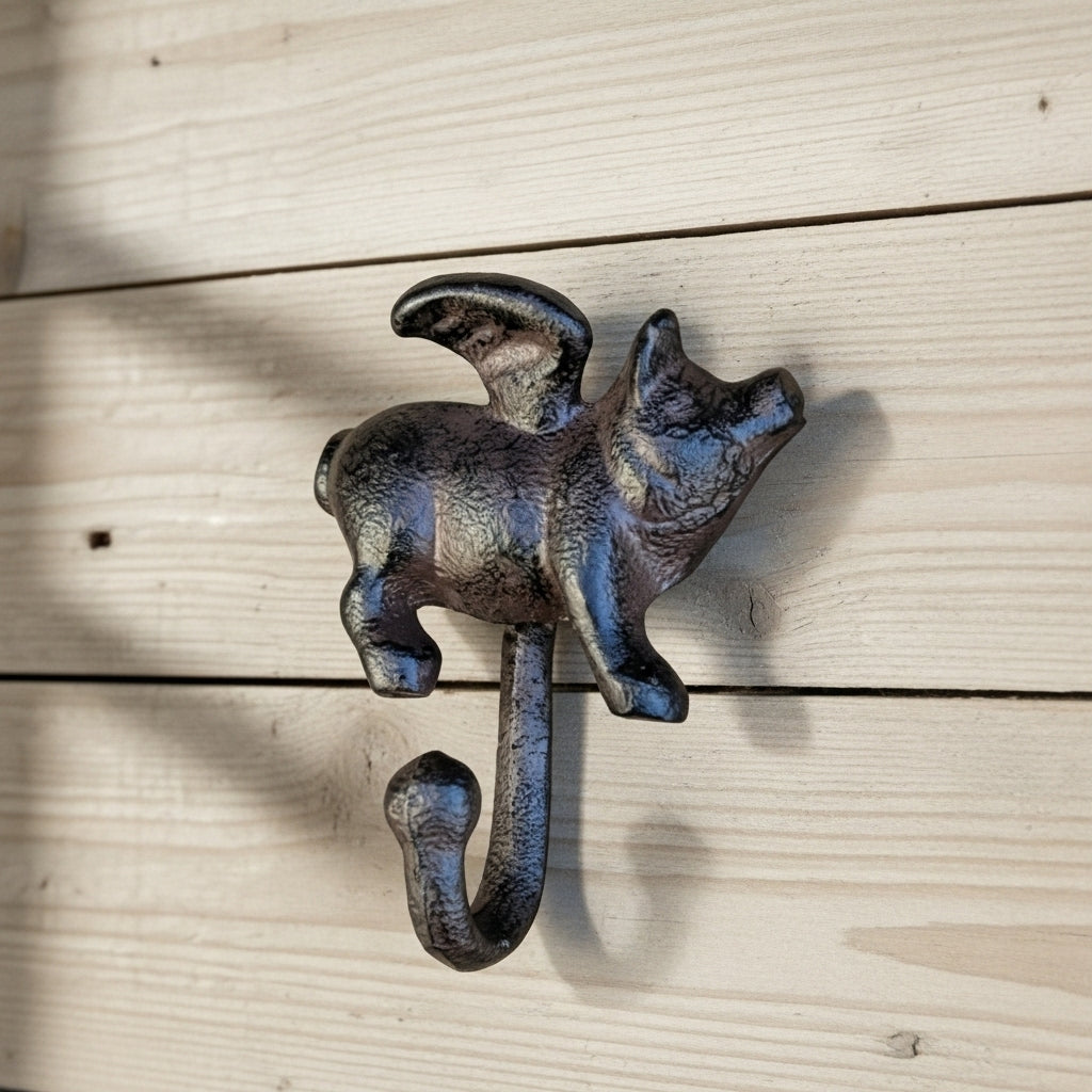Rustic cast iron flying pig wall hook with patina finish on whitewashed wood
