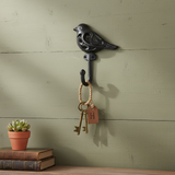 Black cast iron bird hook wall accent with ornate cutout design and curved hanging detail
