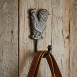 Antique gray cast iron rooster hook mounted on weathered wood, farmhouse wall organizer