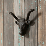 Black cast iron bull head wall hook with curved horns mounted on weathered barn wood siding