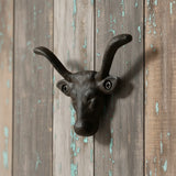 Black cast iron bull head wall hook with curved horns mounted on weathered barn wood siding