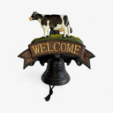 Full cast iron cow welcome bell sign with detailed black and white cow, green moss, and working bell