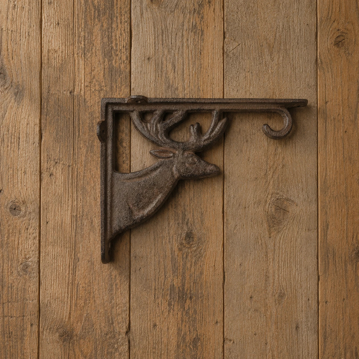 Front view of brown cast iron deer shelf bracket mounted on wood paneling