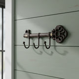 Decorative cast iron key organizer mounted on shiplap wall, dark metal finish