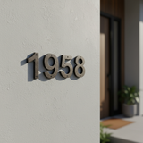 Cast iron address numbers 1958 installed on exterior wall with deep shadow and warm door lighting