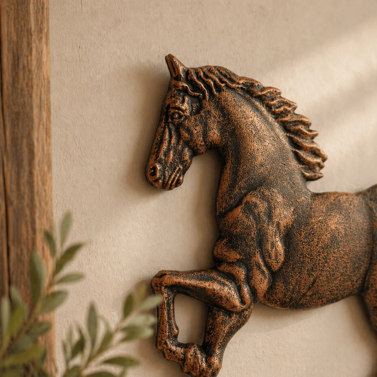 Close view of cast iron running horse wall plaque on beige wall.