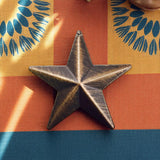 Set of 12 brushed bronze barn stars on colorful patterned background with rustic wall decor styling