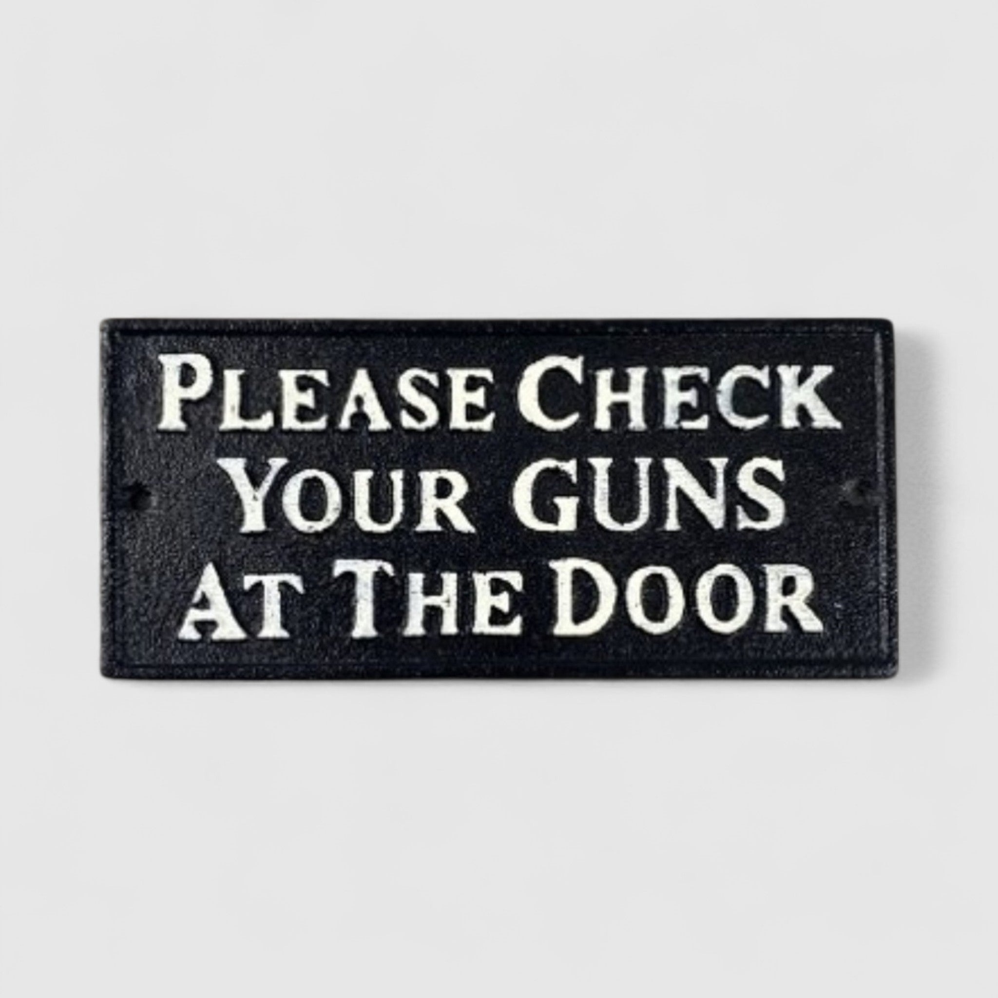 Black cast iron western saloon sign with cream text reading Please Check Your Guns at the Door