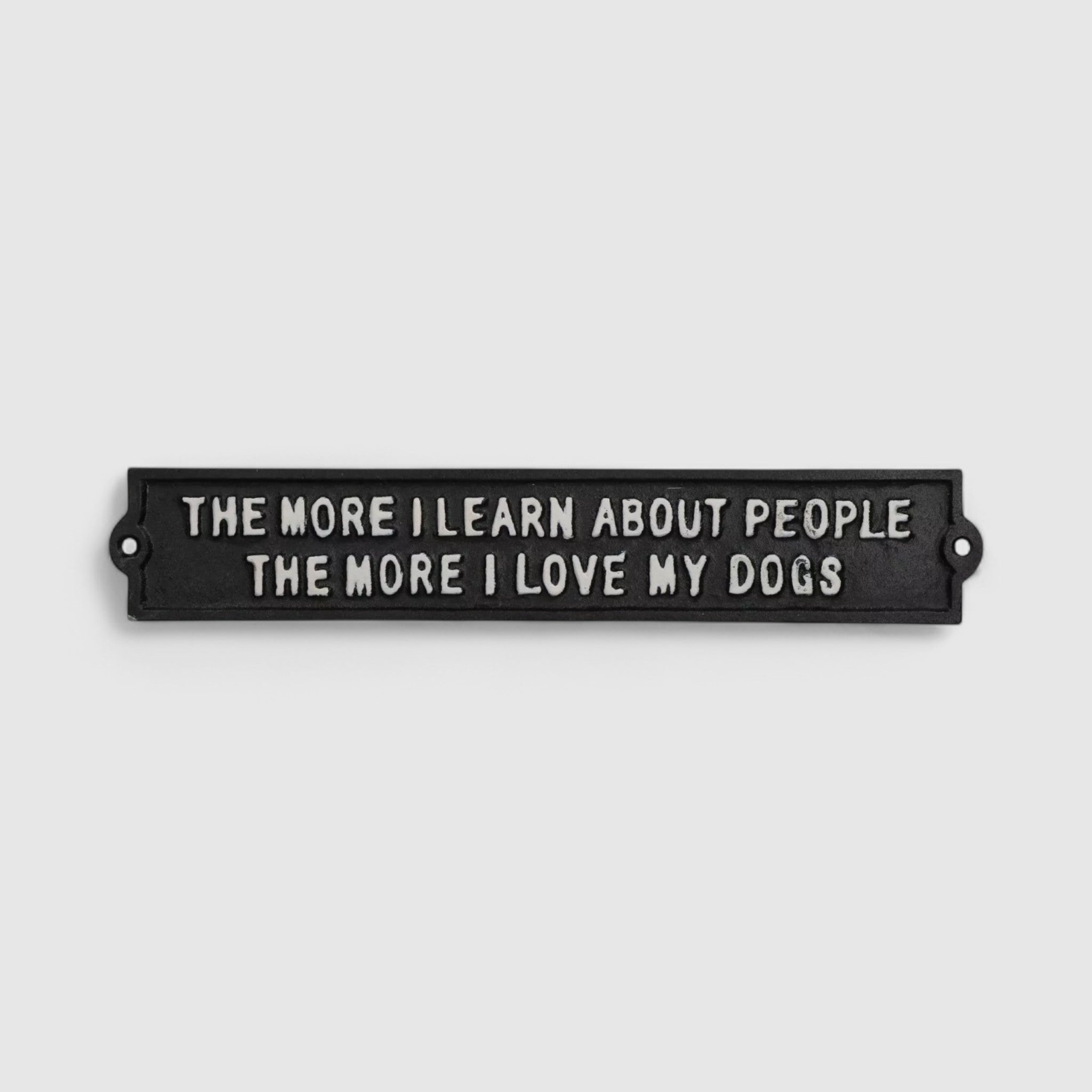 Horizontal black cast iron dog-themed plaque with mounting holes and embossed text on white background