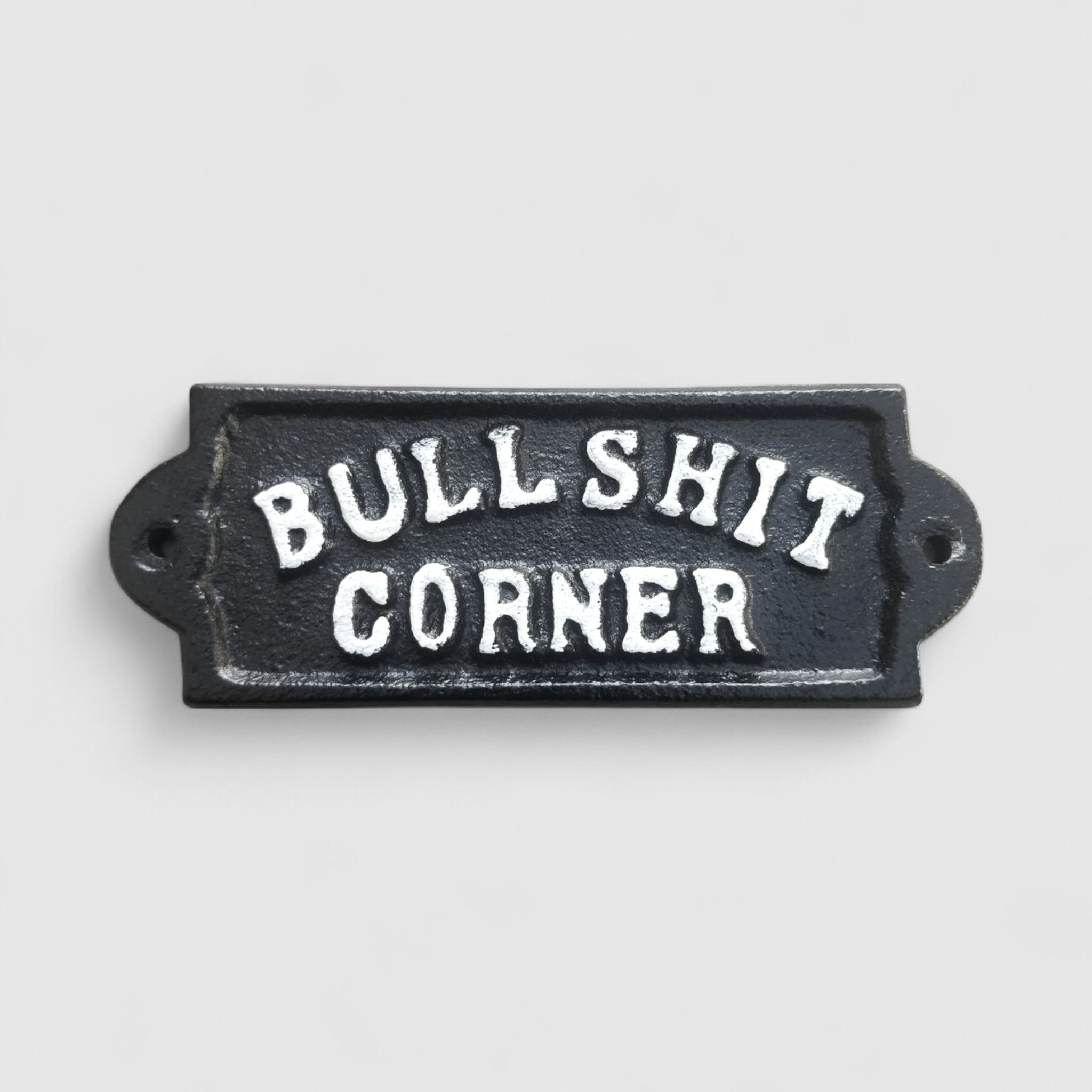 Black cast iron Bullshit Corner sign closeup, embossed white letters, rustic metal plaque