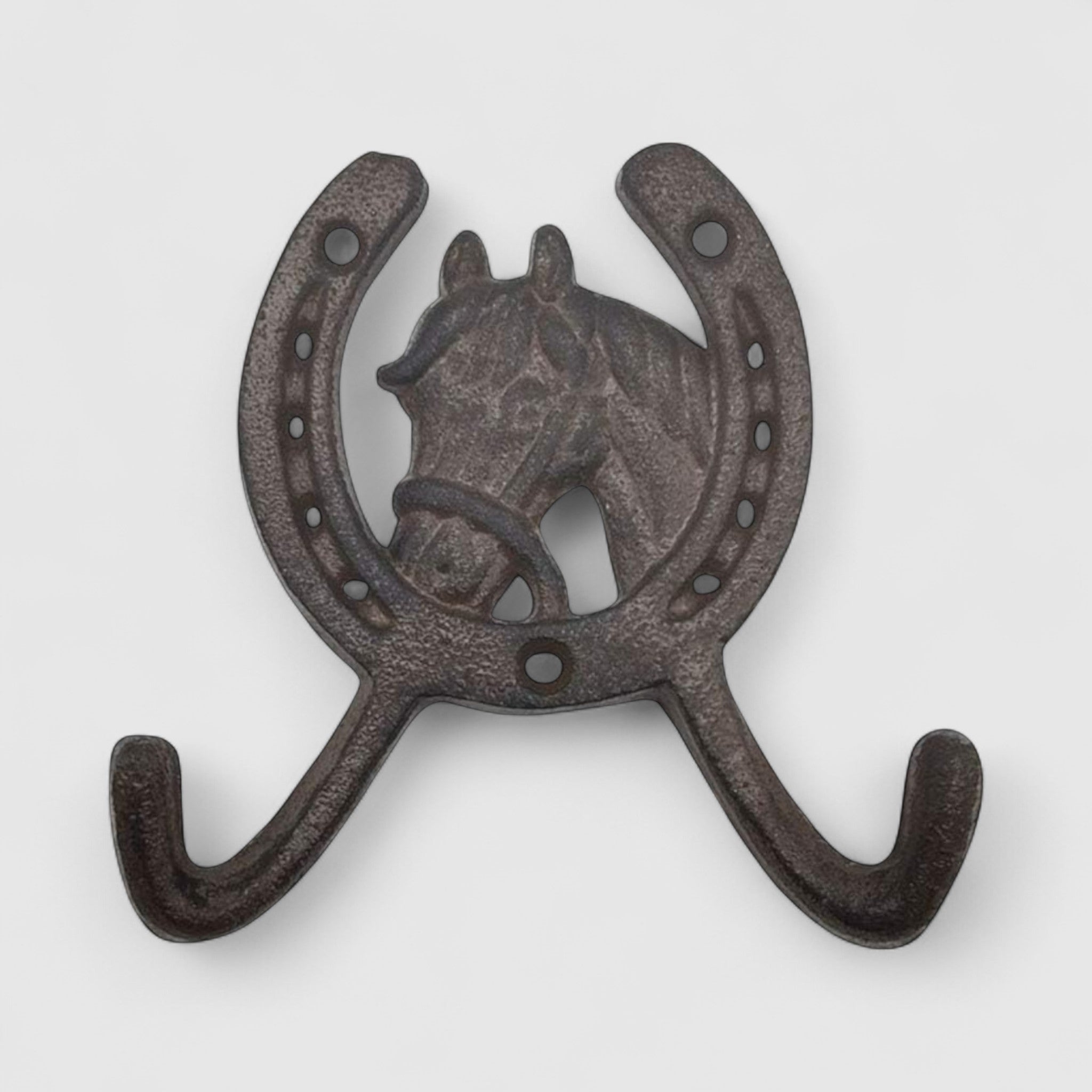 Horse head horseshoe coat hanger cast iron, dark textured finish mounted on white wood