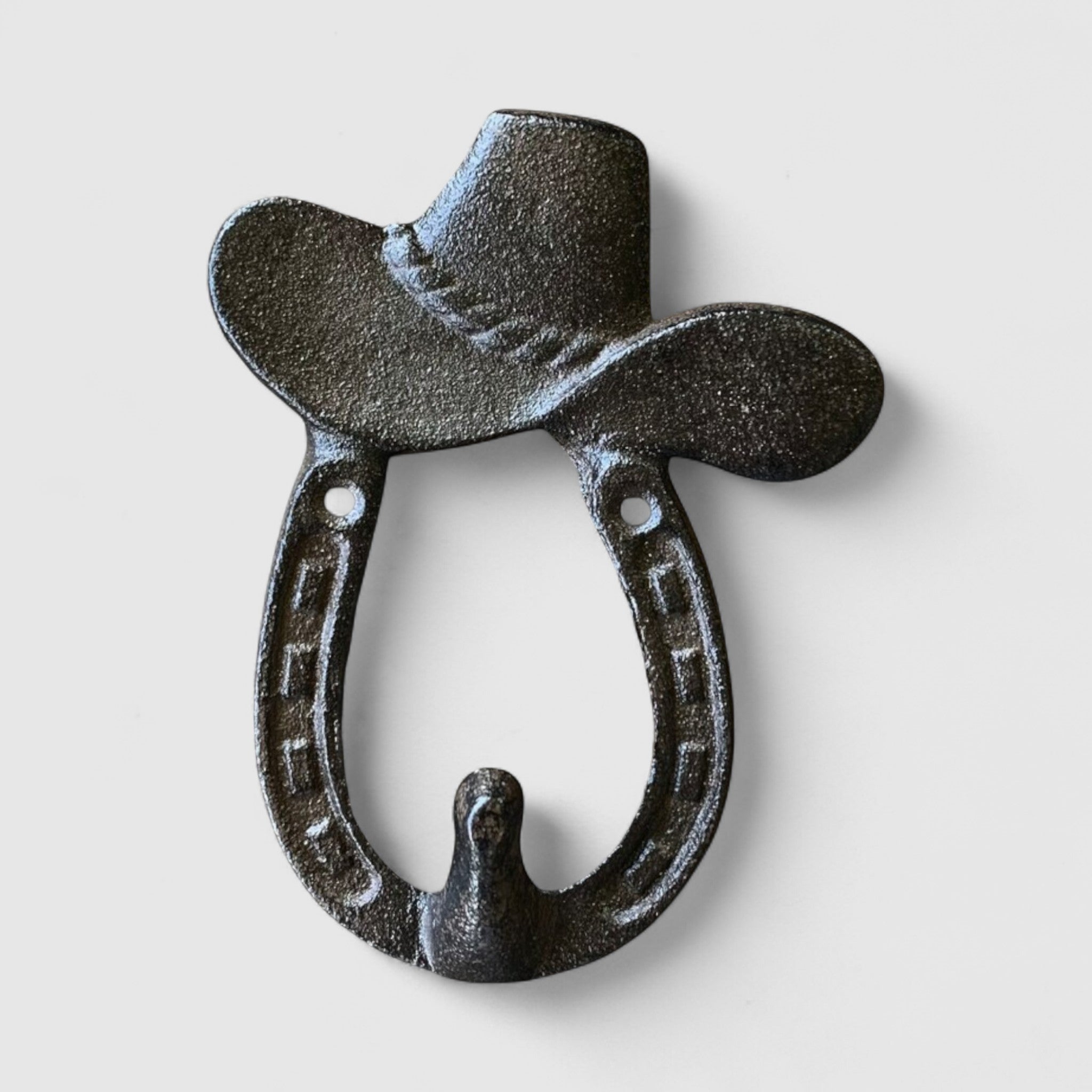 Rustic cast iron hat hook with horseshoe design, mounted on weathered wood wall