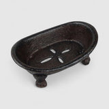 Vintage cast iron soap dish with drainage holes and decorative claw feet, dark finish