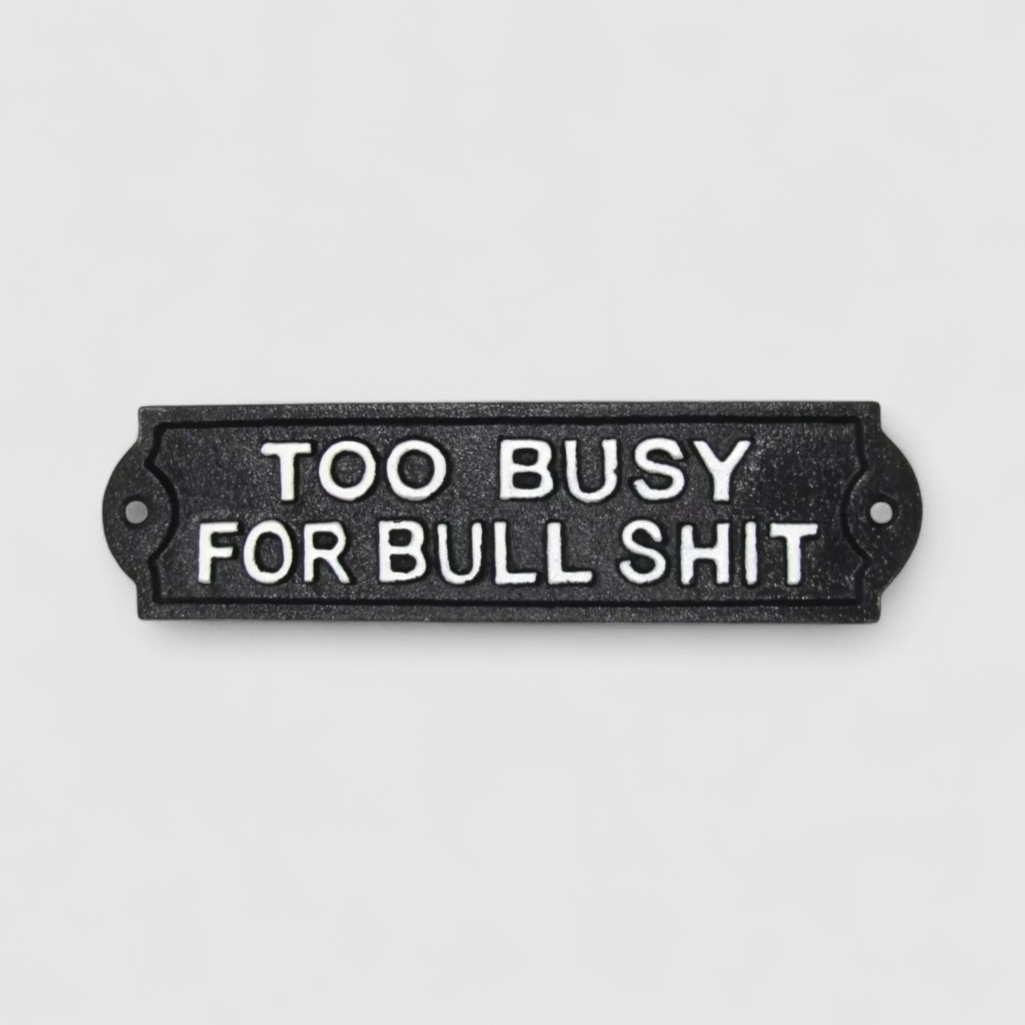 Cast iron too busy for bullshit sign mounted on white painted wooden boards outdoor