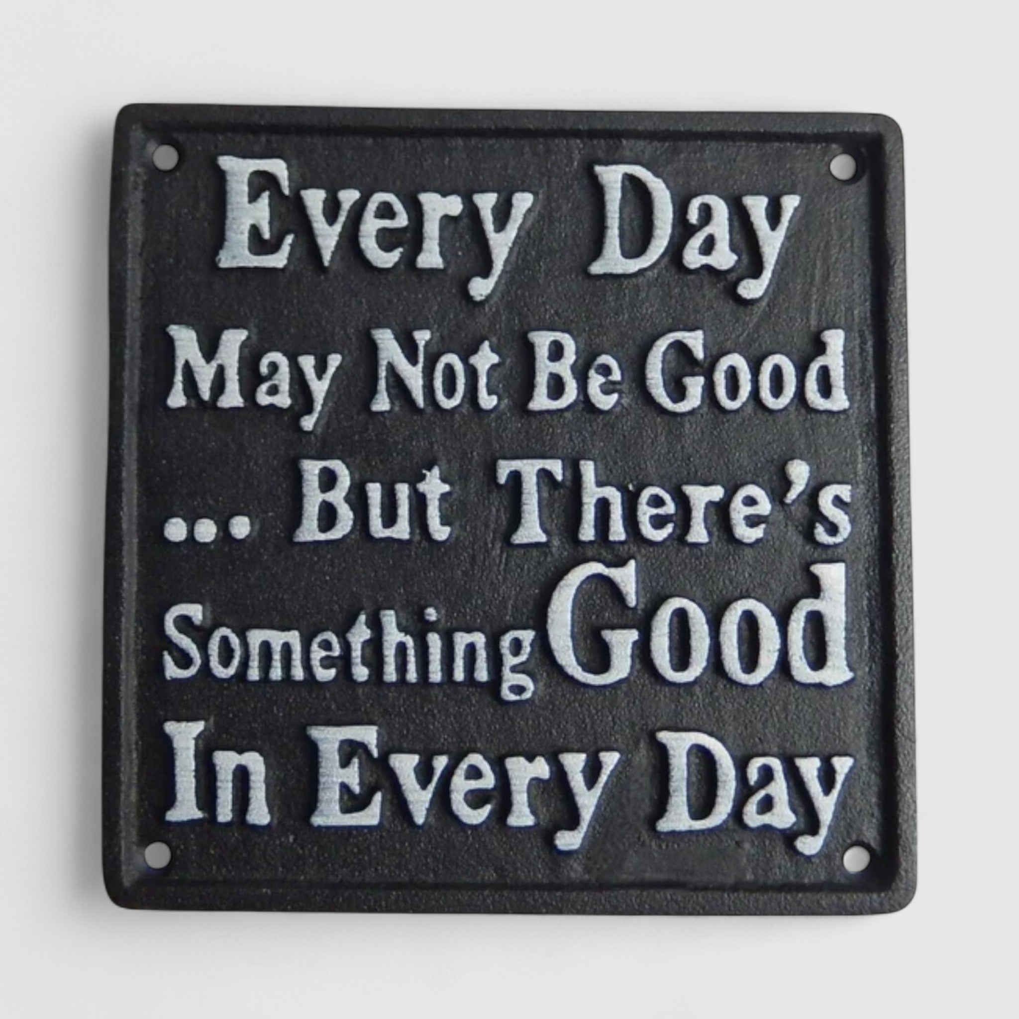 Close-up of black cast iron plaque with motivational quote and mounting holes