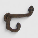 Rustic cast iron wall hook with dual curved arms, weathered brown finish for vintage home decor