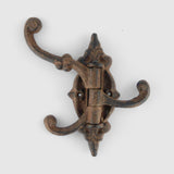 Antique bronze cast iron decorative hook with scrolled arms and ornamental center plate