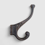 Rustic cast iron hook with dual curved arms, weathered patina, farmhouse wall hanger