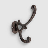 Dark vintage cast iron hook with scrolled bracket arms, rustic wall-mounted hanger