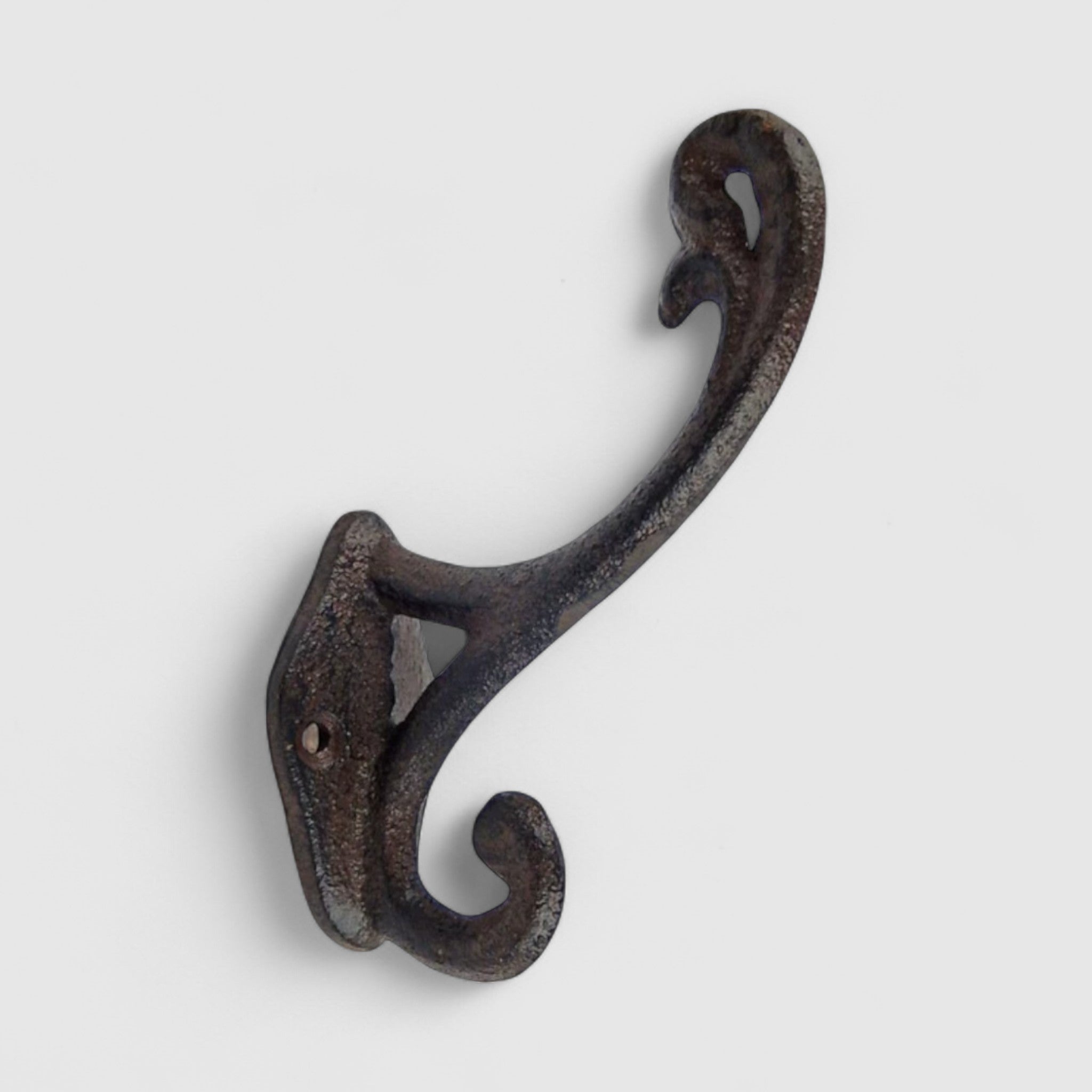Ornate cast iron wall hook with curved scrollwork, dark textured finish for rustic decor