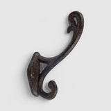 Ornate cast iron wall hook with curved scrollwork, dark textured finish for rustic decor