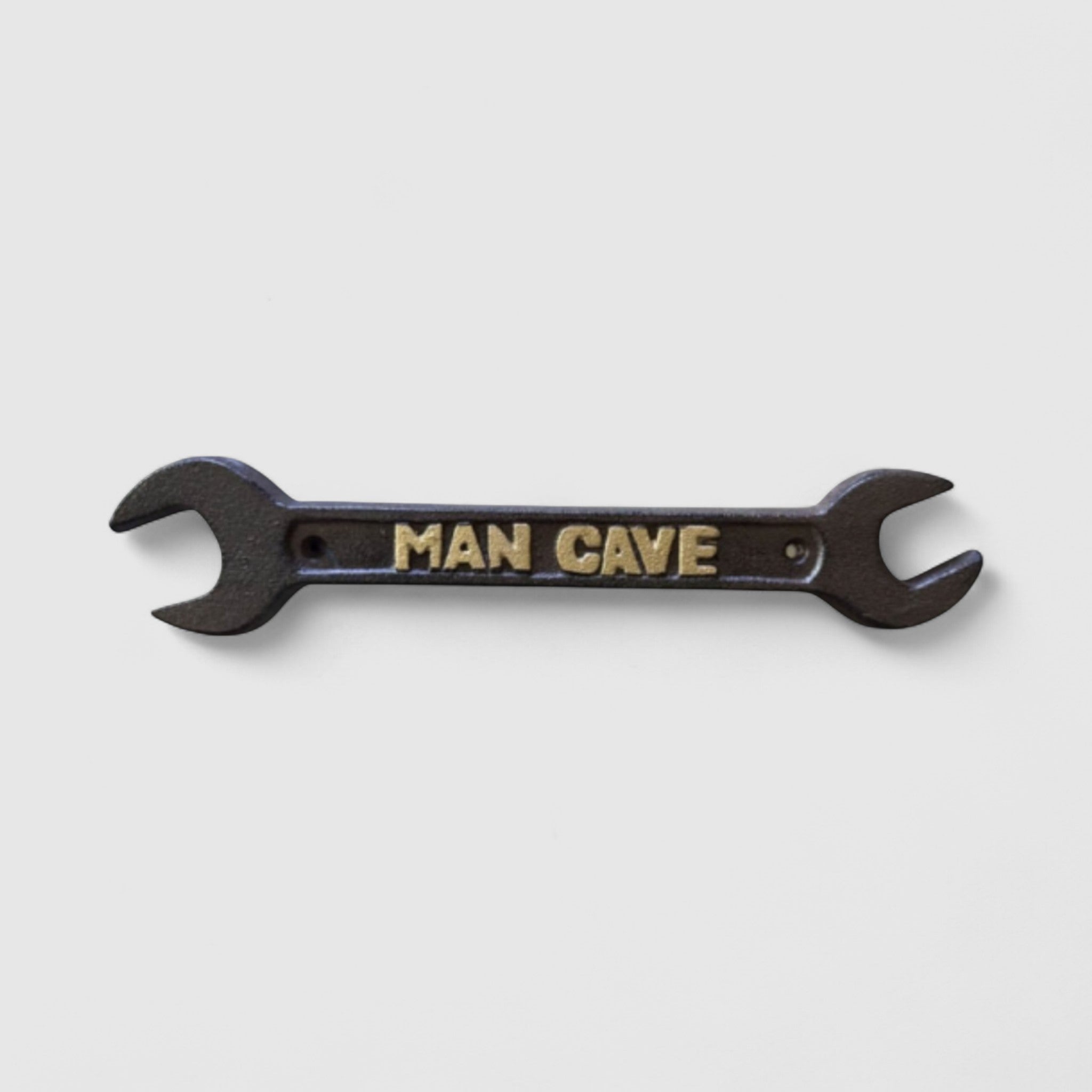 Black cast iron Man Cave wrench decor with embossed gold text on white background
