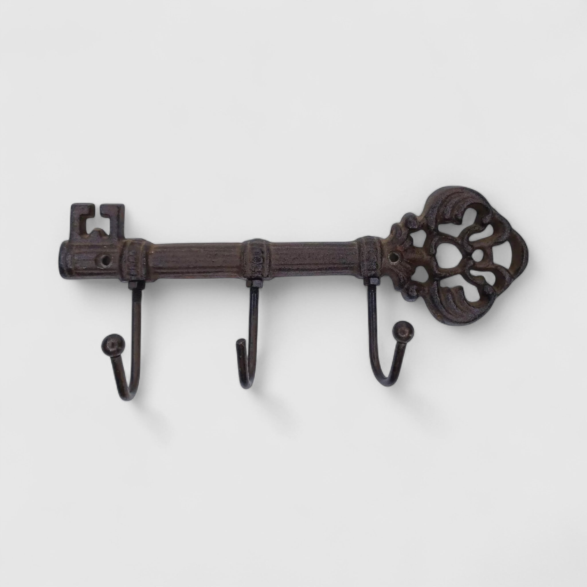 Vintage cast iron key hook rack with ornate scrollwork head and three curved hooks