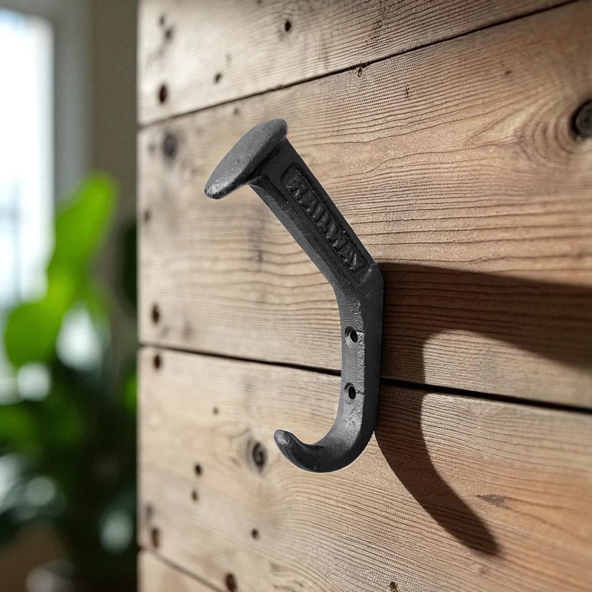 Black cast iron railroad spike hook mounted on wood, rustic industrial decor