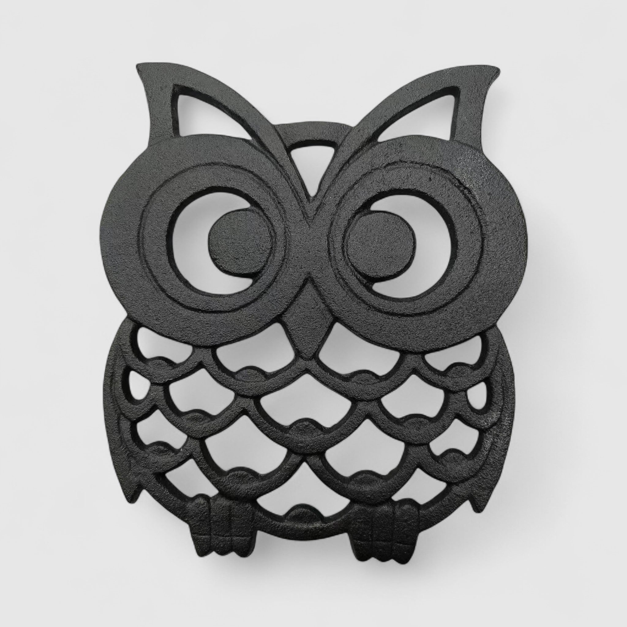 Front-facing cast iron owl trivet with concentric eye rings and textured feather body design