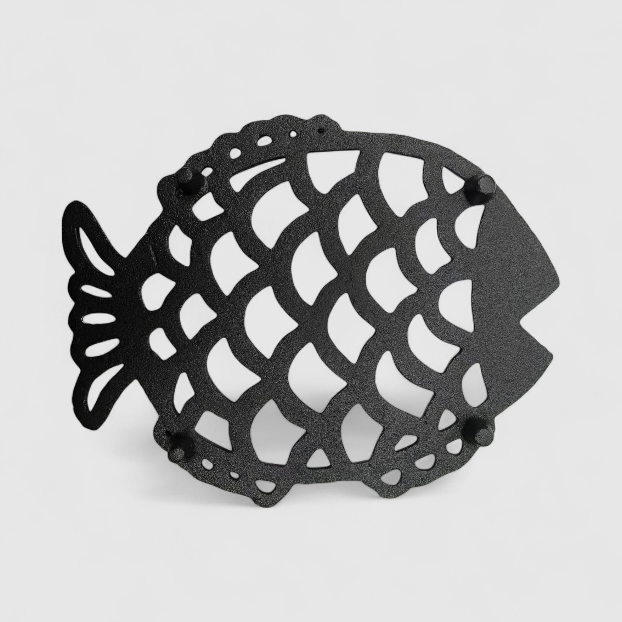 Side angle black cast iron fish trivet showing dimensional relief and scale texture detail