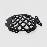 Angled top view dark cast iron fish trivet with openwork scale design and draped tail