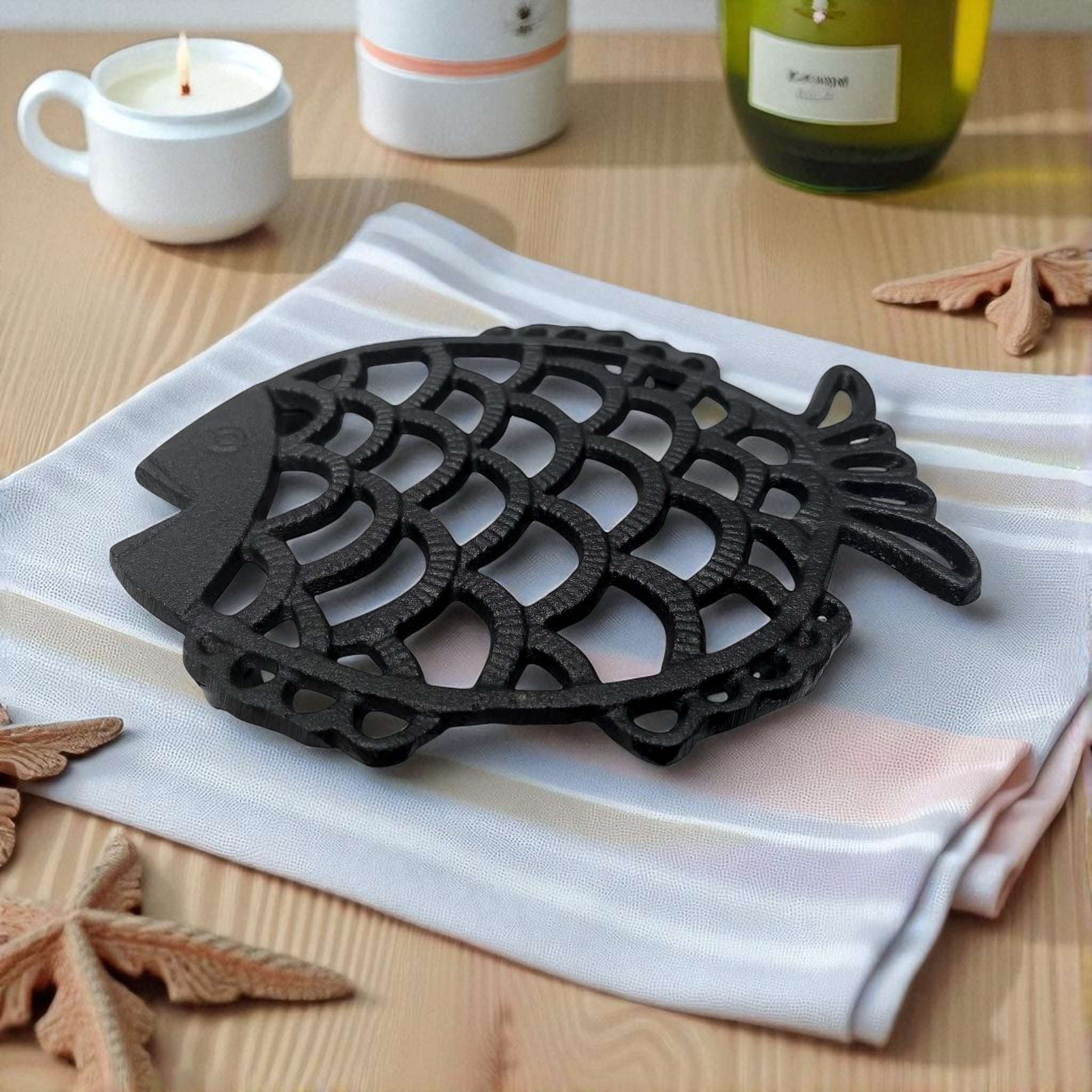 Black cast iron fish trivet on white striped cloth with coastal decor styling