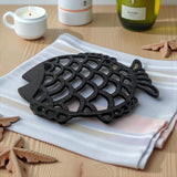 Black cast iron fish trivet on white striped cloth with coastal decor styling