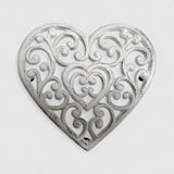 Whitewashed cast iron heart trivet with baroque filigree pattern, flat lay detail