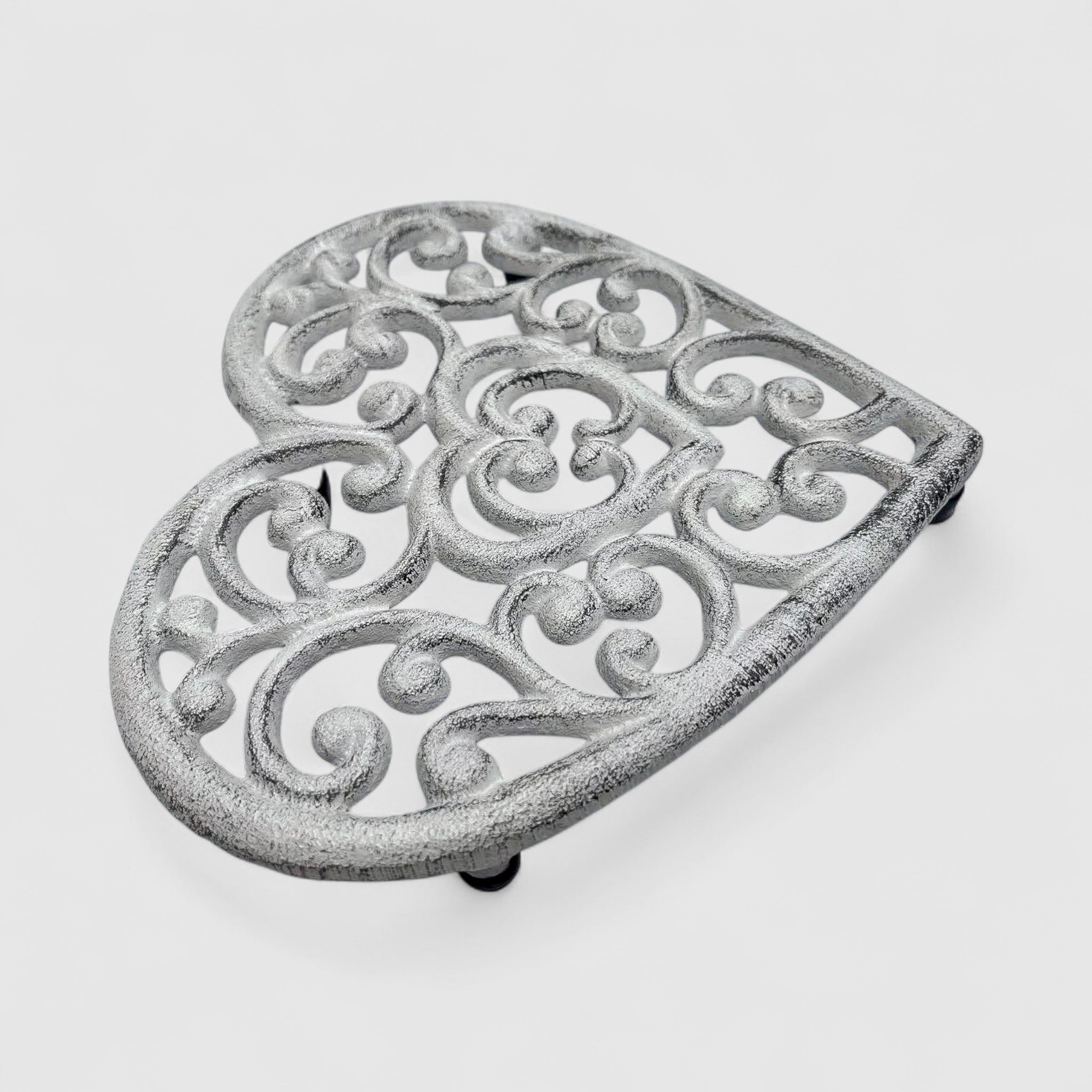 Ornamental white cast iron heart trivet, decorative scrollwork detail angled view