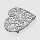 Ornamental white cast iron heart trivet, decorative scrollwork detail angled view